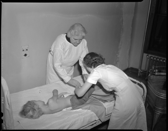 Sister Elizabeth Kenny examining a child and lecturing to visitors.