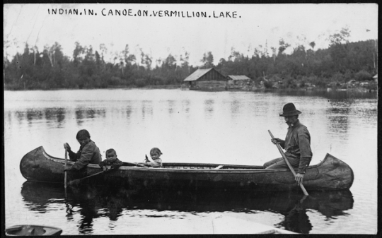 Black and white photograph of an Ojibwe family in canoe on Lake Vermilion, ca. 1905. 