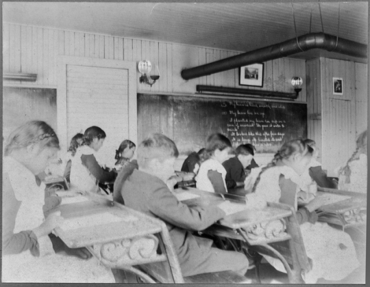 Black and white photograph of “intermediate” students inside a classroom at an Native American boarding school in Beaulieu, c.1900.