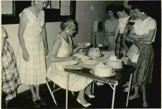 Black and white photograph of a Farm Bureau cake contest, 1960, with Mrs. Milford Peterson (seated) as judge.