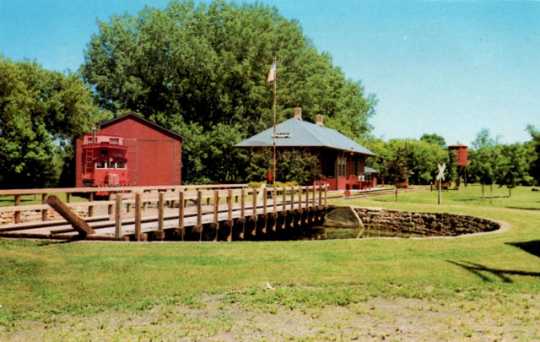 Postcard of the turntable, depot, engine house, and Grand Trunk Western caboose at End-o-Line Railroad Park and Museum, ca. 1980.