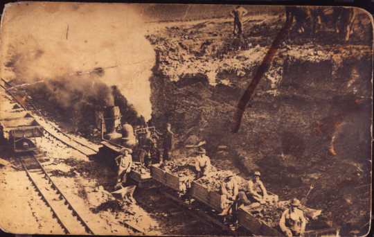 photograph of a train in a clay pit, filled with clay