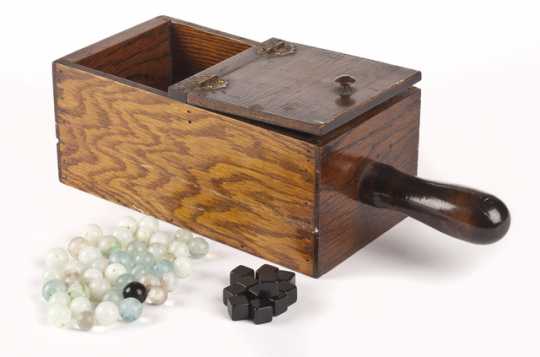 Color image of a wooden ballot box with hinged lid containing forty-two marbles and twelve black plastic cubes. Used by the Minnesota Grange.