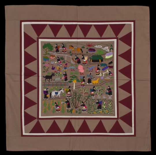 Color image of a Hmong story cloth (paj ndau) showing a traditional Laotian village scene. Made in Ban Vinai, Thailand, c.1989.