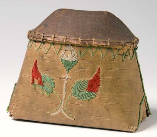 Miniature birchbark makak (Ojibwe storage basket) decorated in floral motifs employing colored cord and yarn. The makak is filled with maple sugar.