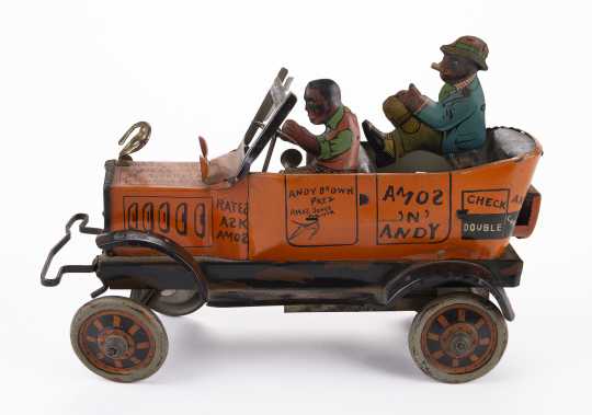 Metal windup toy car model of the Fresh Air Taxicab from the radio show Amos 'n Andy, made by Louis Marx and Co. of New York. It features two caricatured men riding in the car, the driver is wearing an orange vest, while the passenger wears a blue jacket and smokes a cigar. Made sometime between 1930 and 1939.