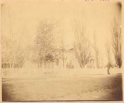 Black and white photograph of three individuals standing in front of Singer's Hall, Young America, 1870s or 1880s.