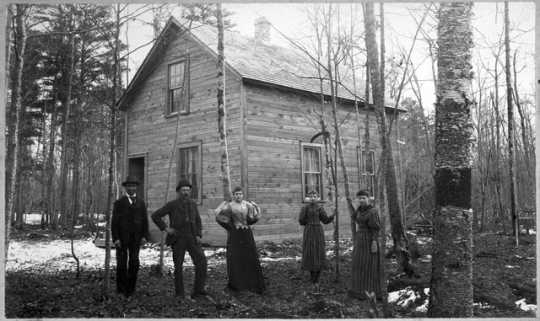 People posed in front of a house built for Hinckley fire victims, after September 1, 1894.