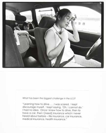 Black and white photograph of a woman driving a car with a child in the backseat, with accompanying quote, by Jane Kramer, 2004. From collection, "Photographs and Stories of Refugee Women: Perseverance, Dignity, Strength, Hope, and Peace."