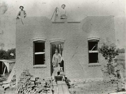 Black and white photograph of a brick house under construction in Meire Grove c.1890.