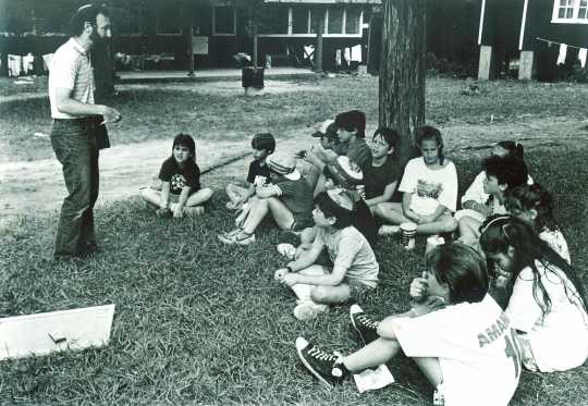 Black and white photograph of campers gathering outdoors at Camp Ramah, 1986.