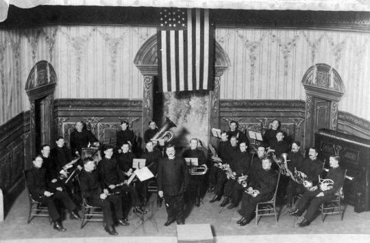 Black and white photograph of Director Arthur Wasshausen leading the Citizens Band in Crookston's opera house in 1907.