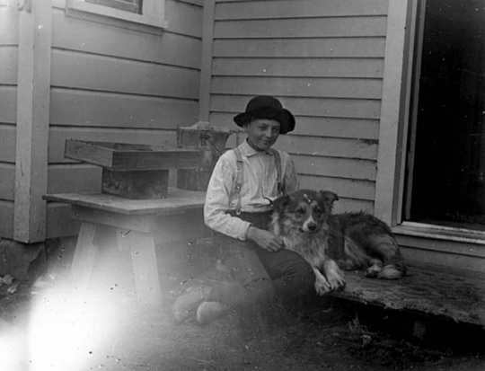Black and white photograph of Lewis H. Merrill and his dog Mack at the backdoor of the Harrington-Merrill House, 1900.