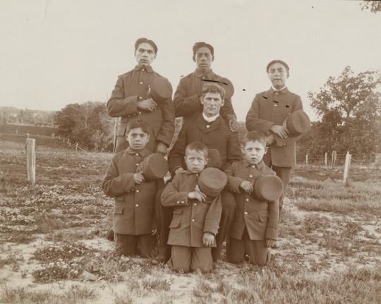 Black and white photograph of students and a teacher at a Native Americann boarding school, c.1900.