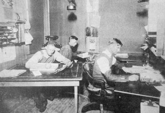 Black and white photograph of the depot agent, engineer, and telegraph operator working inside the Westbrook Depot, 1916.
