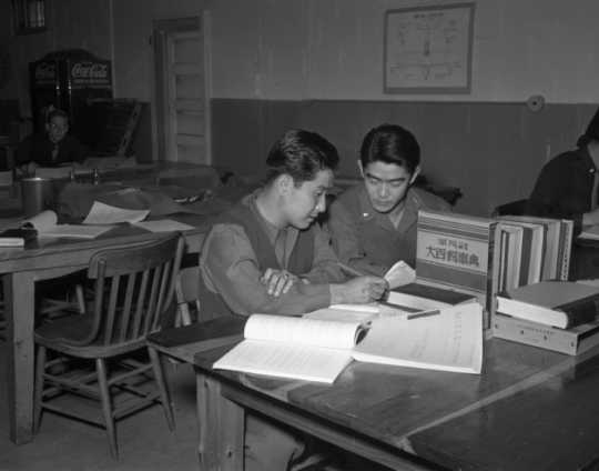Black and white photograph of MISLS students Isami Osato and George Sakanari translating Japanese civil service regulations into English at Fort Snelling, c.1944.