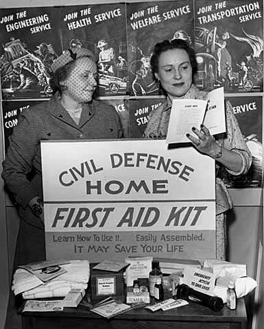 Black and white photograph of women with civil defense home first aid kit display, 1954.