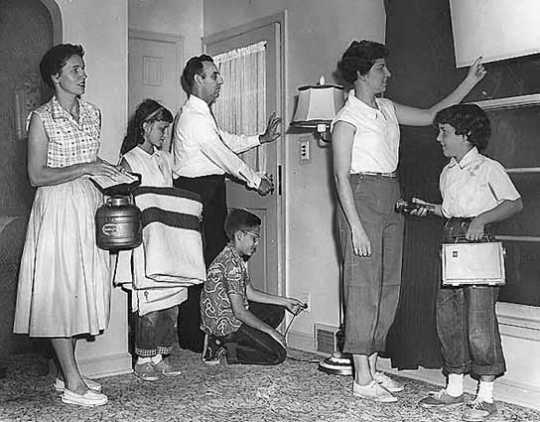 Black and white photograph of the Gerlach family at their home during a civil defense drill,1956.