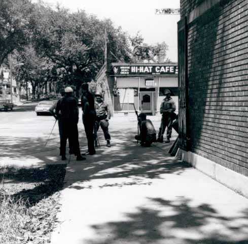 Police standing near a building on Plymouth Avenue in Near North Minneapolis during an episode of civil unrest in the neighborhood, ca. 1967. Photo by Twiggs.
