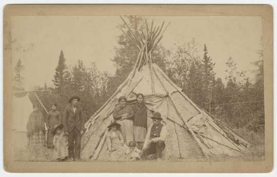 Group of Ojibwe in front of a wigwam at Grand Portage