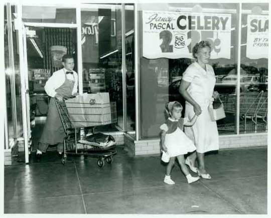 Employee Dick Liecting pushing a grocery cart for two shoppers at the Red Owl Store, Southdale Mall, Edina. 