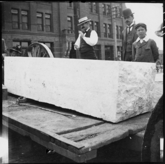 People standing beside stone used for the Capitol