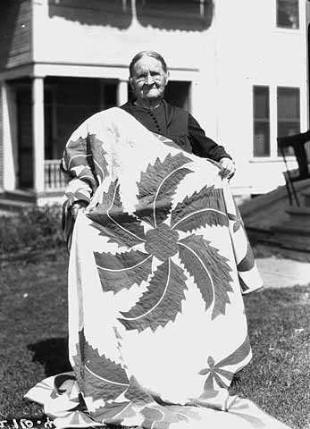 Black and white photograph of woman with prize-winning quilt, 1926. 