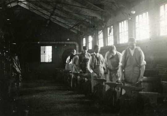Black and white photograph of an Agriculture Extension, Short Course in Blacksmithing; men at the forges, 1908.