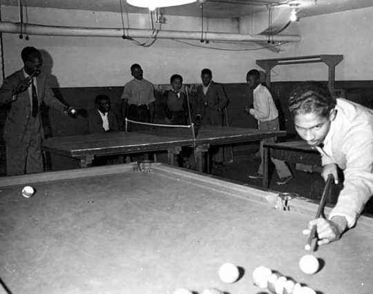Black and white photograph of people playing table tennis and billiards at the Phyllis Wheatley House, ca. 1940.
