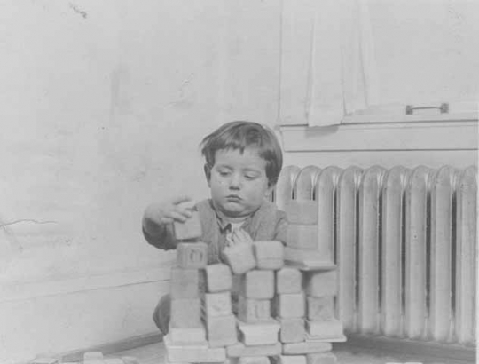 Black and white photograph of a toddler playing with blocks at the Northeast Neighborhood House, c.1925. 