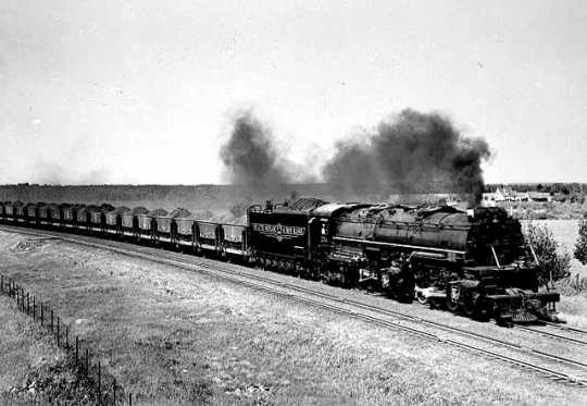 Black and white photograph of a ellowstone locomotive pulling a string of jennies near Duluth, 1940. 