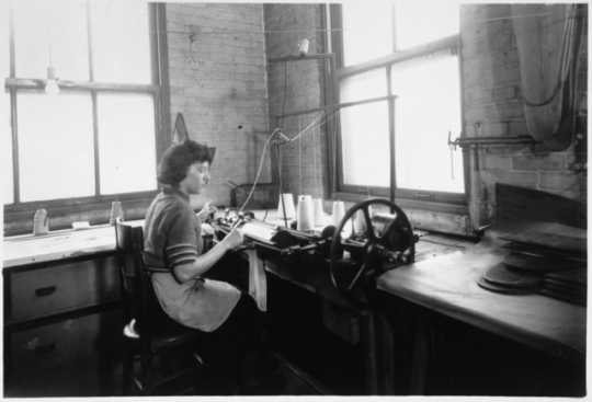 Black and white photograph of an employee knitting a sock to cover an amputated limb, Winkley Artificial Limb Company, Minneapolis, 1937. 