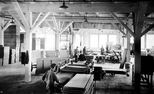 Black and white photograph showing the interior of a lumber mill, ca. 1915.