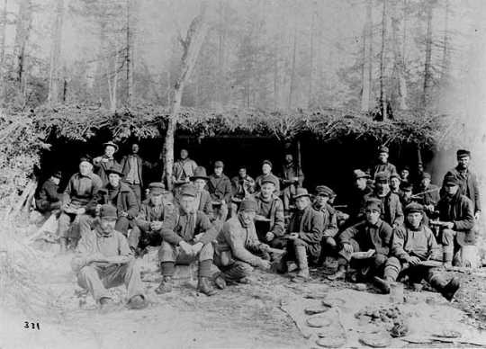 Black and white photograph of a Lumber crew eating outdoors, ca. 1900. Photograph by A.A. Swan.