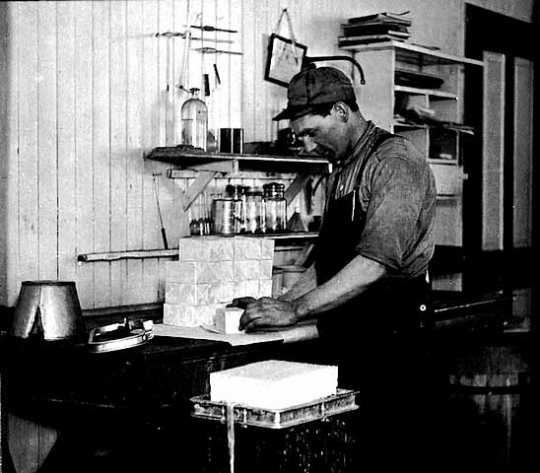 Black and white photograph of a worker packing butter at a creamery in Hawley, c. 1917.