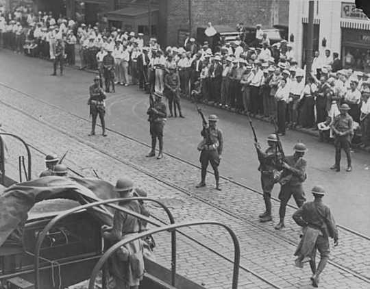 Black and white photograph of National Guard troops keeping a crowd back during a raid on strike headquarters in Minneapolis, 1934.