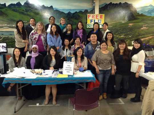Color image of participants in the Operation Free Flu Shot program gather for a group photograph at the Hmong New Year celebration in St. Paul’s RiverCentre on November 24, 2012.