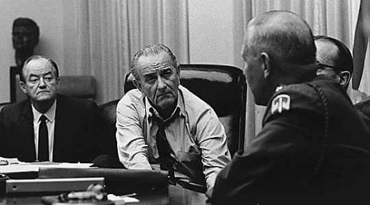 Black and white photograph of Vice President Humphrey discussing the Vietnam War with President Johnson and military officials, c.1965.