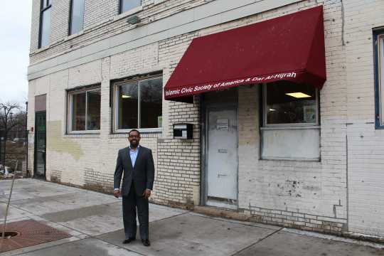 Color image of Wali Dirie, executive director of the Islamic Civic Society of America and Dar Al-Hijrah Mosque, stands outside their new entrance at 504 Cedar Avenue, 2015.