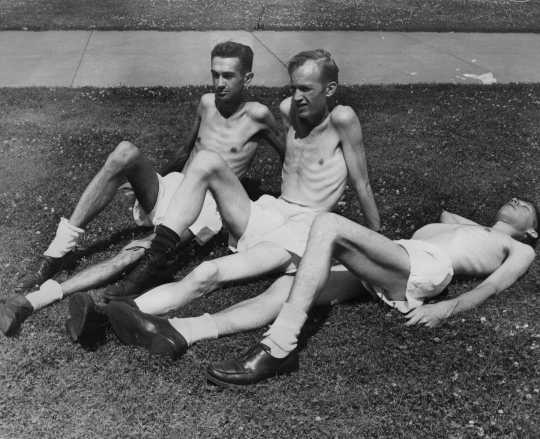 Black and white photograph of volunteers Gerald Wilsnack, Marshall Sutton, and Jasper Garner relax in the sun between their daily routine, c.1944.