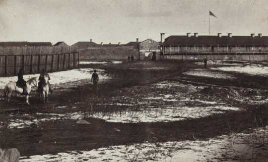 Black and white photograph the south side of Fort Snelling showing the gatehouse and shops, c.1864.