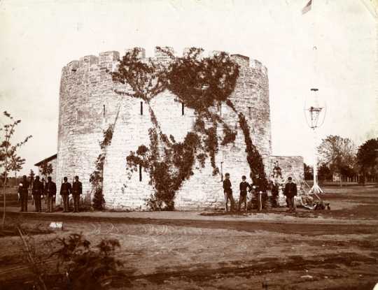 Black and white photograph of African American troops and officers of the Twenty-fifth Infantry standing by the Round Tower, c.1887.