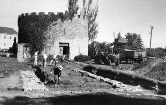 Black and white photograph of an archaeological crew and mechanical equipment near the Round Tower, 1958.