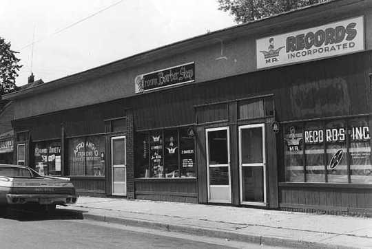 Black and white photograph of Businesses near the intersection of East 38th St and 4th Ave, Minneapolis, 1975.