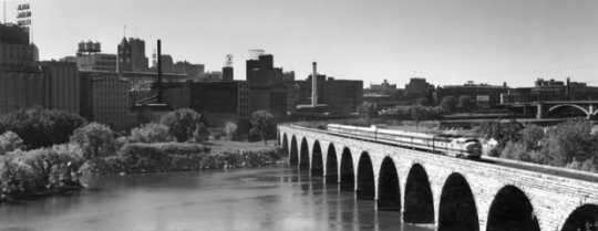 Black and white photograph of the Great Northern Railway’s Winnipeg Limited crossing the Stone Arch Bridge, Minneapolis, ca. 1955.