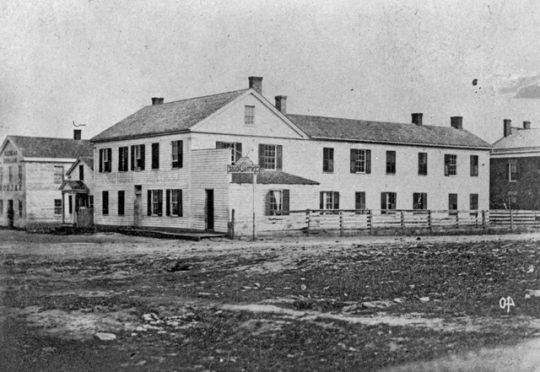 Black and white photograph of the Central House (where the Territorial Legislature met prior to the building of the State Capitol) and First State Capitol, St. Paul, ca. 1850.