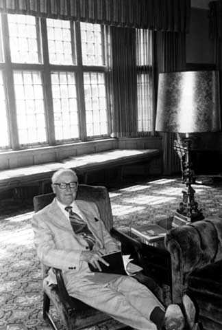 Black and white photograph of Sy Mergens relaxing in the Fireside Room of the University Club, June 22, 1977. Photographed by Julian G. Plante.