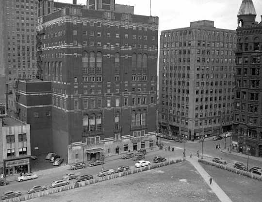 Black and white photograph of the St. Paul Athletic Club and surrounding buildings. View of the intersection of Fourth Street East and Cedar Avenue, St. Paul. The St. Paul Athletic Club is at center left.