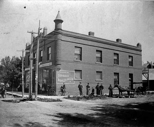 Black and white image of the Office of Faribault Woolen Mills, founder Carl H. Klemer standing to right of bicycle, 1897.
