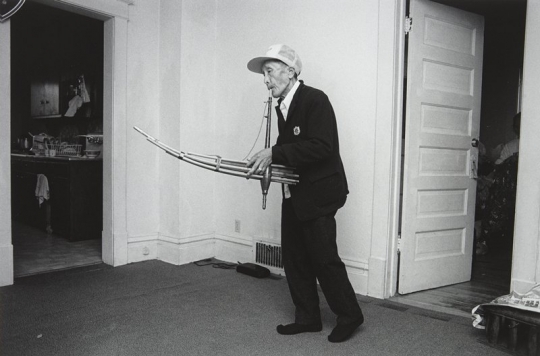 Black and white photograph of a man Playing the Kheng, Frogtown, 1994. Photograph by Wing Young Huie.